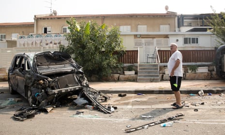 A man stands near a burned car after a battle between Israeli troops and Hamas militants in Sderot, Israel