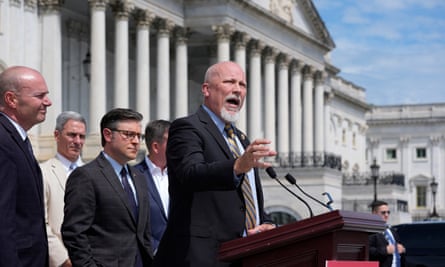 Middle-aged white men in suits speak on the steps on a white stone building with many columns.