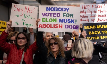 Protesters hold placards that say ‘say no to Tesla’ and ‘nobody voted for Elon Musk! Aboish Doge’