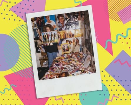 An old photo of a girl standing holding an open teen magazine showing a boy band, in a bedroom plastered with pages from teen magazines