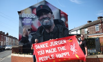 Fans pose with a banner in front of a mural of Liverpool manager Jurgen Klopp