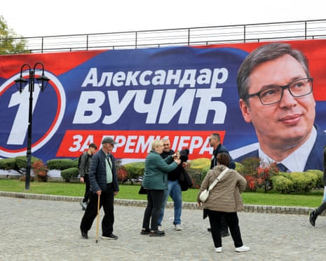People take photos near a campaign banner of Aleksandar Vučić in Serbia