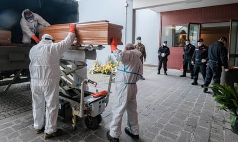 Soldiers wearing protective suits lift a coffin on to a military truck in March 2020.