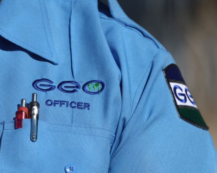 A closeup of the chest pocket of a person wearing a blue work shirt, with the words “Geo officer” embroidered above a couple pens.