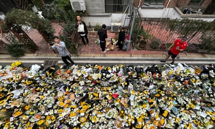 Residents take pictures as they walk past flowers laid outside a residential building where Li Keqiang spent his childhood in Hefei city, Anhui province, China.