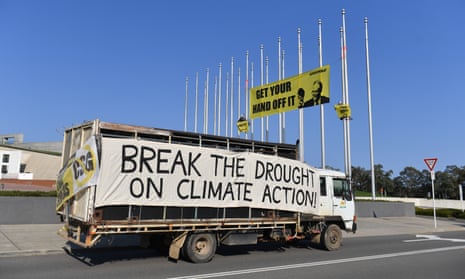 Greenpeace activists protesting against climate change unfurl a banner on the flagpoles outside Parliament House on Monday.