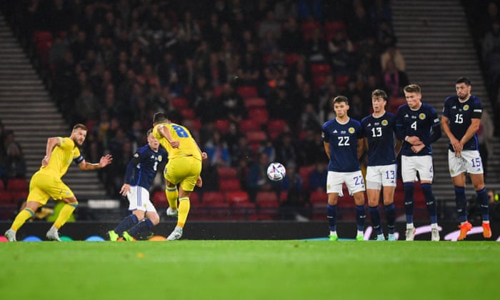 Ukrainian midfielder Ruslan Malinovskiy scores a free kick against Scotland's wall.