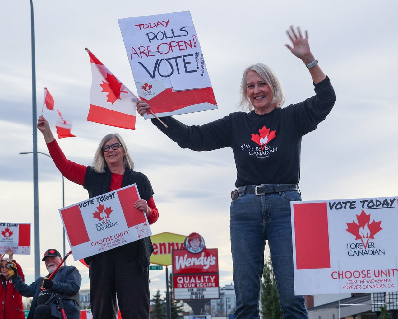 Forever Canadian supporters wave flags and hold signs urging people to vote in Calgary