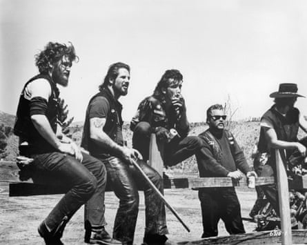 Sonny Barger and other Hells Angels sit on a wooden fence