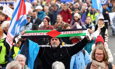 A man holds aloft a Palestine scarf during a protest march