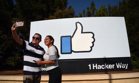 people pose for a selfie in front of the Facebook “like” sign at Facebook’s corporate headquarters in Menlo Park, California.
