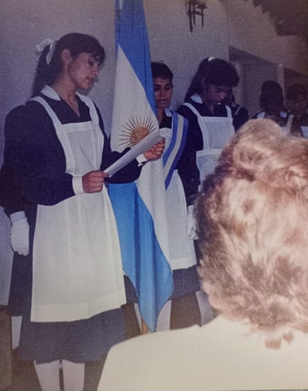 A photo of young women in old-fashioned maids’ uniforms standing next to an Argentinian flag