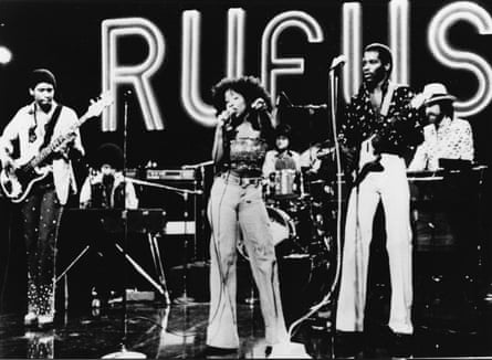 The band Rufus play on a TV show in the 70s with their name lit up behind them.