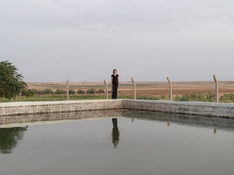A woman stands next to an artificial body of water