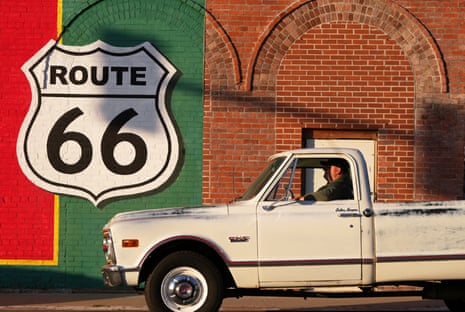 A motorist pulls up to a stop light in front of a Route 66 sign