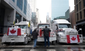 Truck drivers hang a Canadian flag on the front grill of a truck parked in downtown Ottawa near Parliament Hill on Wednesday, Feb. 2, 2022.