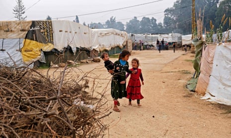 Two young girls and a baby (in arms of older girl) in a refugee camp.