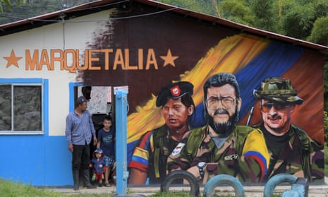 A man and two children stand next to a mural of late Farc commander Alfonso Cano, center, in Colombia.