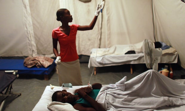 Nurse Ruth Saint Aimé helps Jeff Louissait as he lies on a cot while being treated for cholera in the German Red Cross cholera treatment facility on 22 November 2010 in Archaie, Haiti.