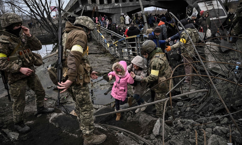 People cross a destroyed bridge as they leave the city of Irpin, north-west of Kyiv, during heavy shelling and bombing