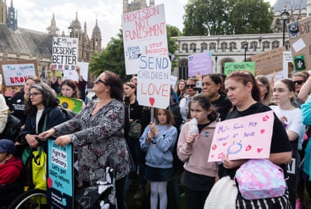 People stand holding placards and banners with slogans including ‘Send children love’ and ‘Provision not punishment’.