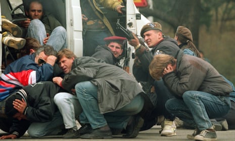 A Bosnian soldier returns fire in downtown Sarajevo as he and civilians come under fire from Serbian snipers, April 1992.