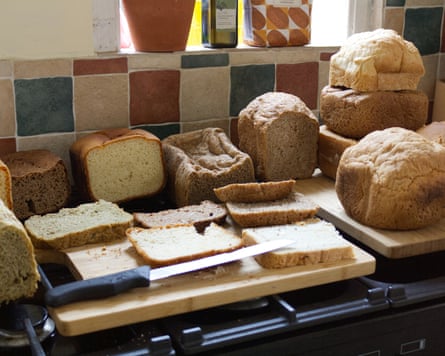 Several loaves of bread, some sliced, sit on cutting boards with a knife on a stovetop