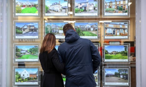 Couple look at pictures in estate agent's window