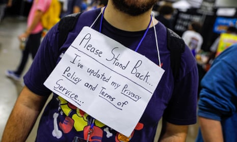 Photograph of a man wearing a sign reading 'please stand back: I've updated my privacy policy and terms of service'