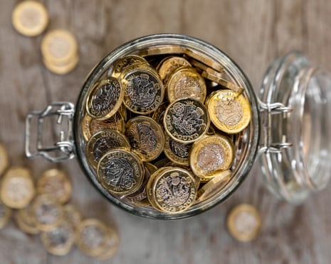 A glass jar with a hinged lid filled with one pound coins, viewed from above