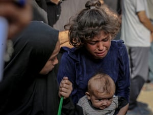 A child holding a baby weeps