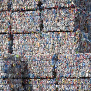 Bound bales of crushed plastic bottles and containers sit stacked ready to be recycled at a recycling centre.