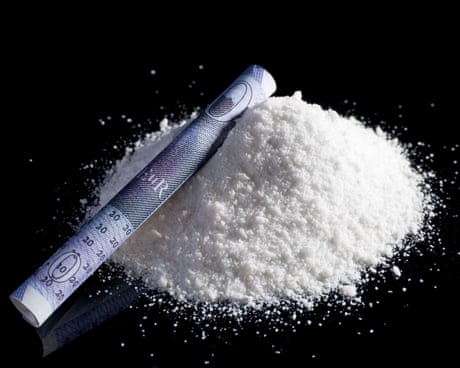 powder on black background with rolled up twenty pound note