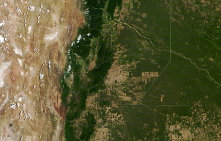 An aerial view shows a large patch of brown land blend into green, with small rectangles of brown land in the middle