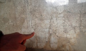 An archaeologist points to engravings on the wall of the Casa della Nave Europa in Pompeii.
