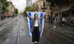 A woman holding a blue and white flag in the middle of the street