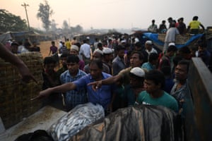 Refugiados de Rohingya acenam para vendedores de peixe de Bangladesh no mercado de peixe do amanhecer no campo de refugiados de Kutupalong