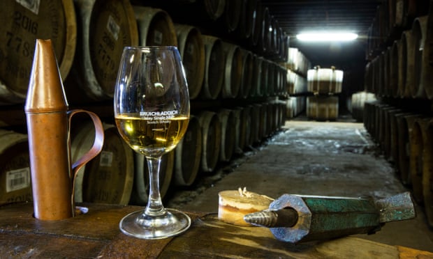 A whisky tasting glass and barrels