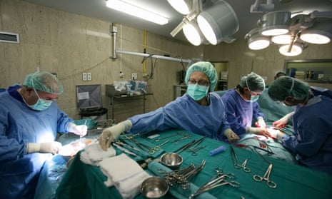 Doctors performing legitimate organ transplant surgery in an operating room of a UK hospital.