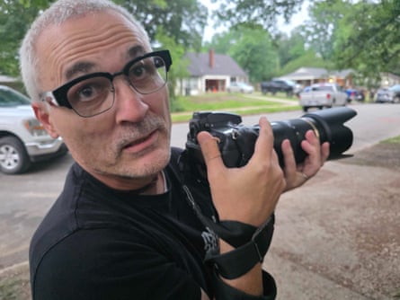 A man with glasses holding a camera.