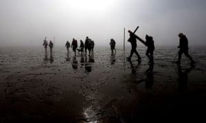 Berwick-upon-Tweed, UK. Christian devotees celebrate Easter as they walk over the tidal causeway to Lindisfarne during the final leg of their Good Friday pilgrimage