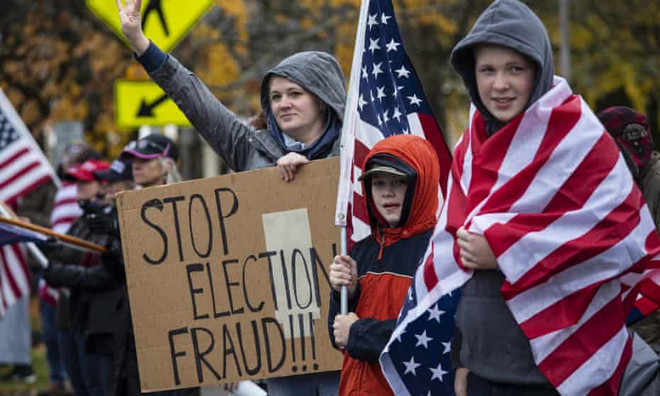 Supporters with American flags hold a sign that reads, "Stop election fraud!!!" at a Stop the Steal rally on 14 November 2020.