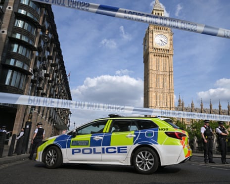 A police car is parked on a cordoned-off street near Big Ben, with officers standing nearby