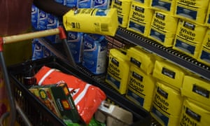 Packets of sugar on shelves and shopping trolley of items including flour