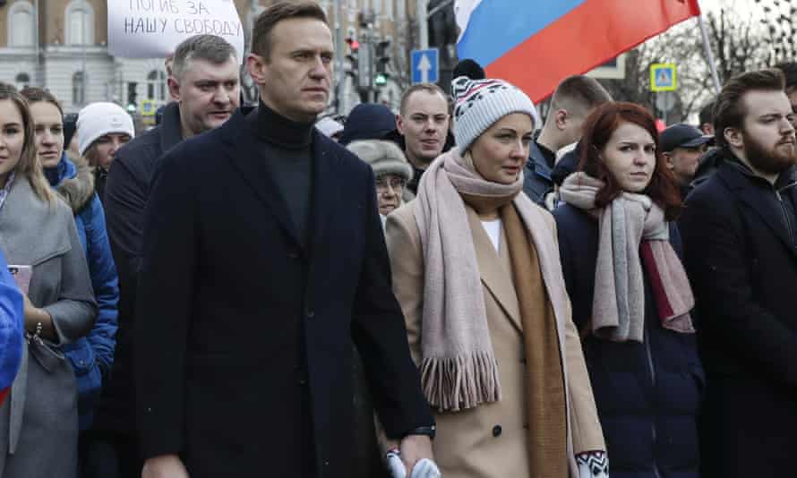A man and a woman surrounded by people holding banners