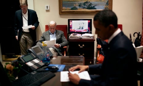 Vice-President Joe Biden and President Barack Obama review documents as a television displays an image of Osama bin Laden.