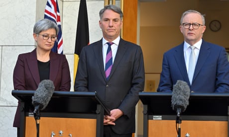 Penny Wong, Richard Marles and Anthony Albanese standing behind lecterns at a press conference