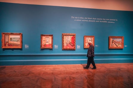 a man walking by a wall filled with paintings