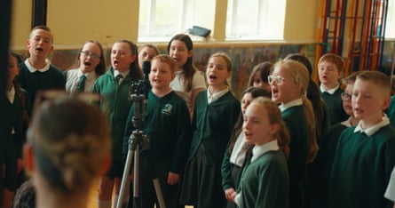 Children in school uniform singing in a classroom