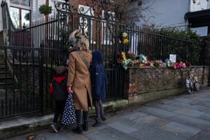 A woman and young boys view flowers and tributes outside the home and studio of Vivienne Westwood  following her death this week in London